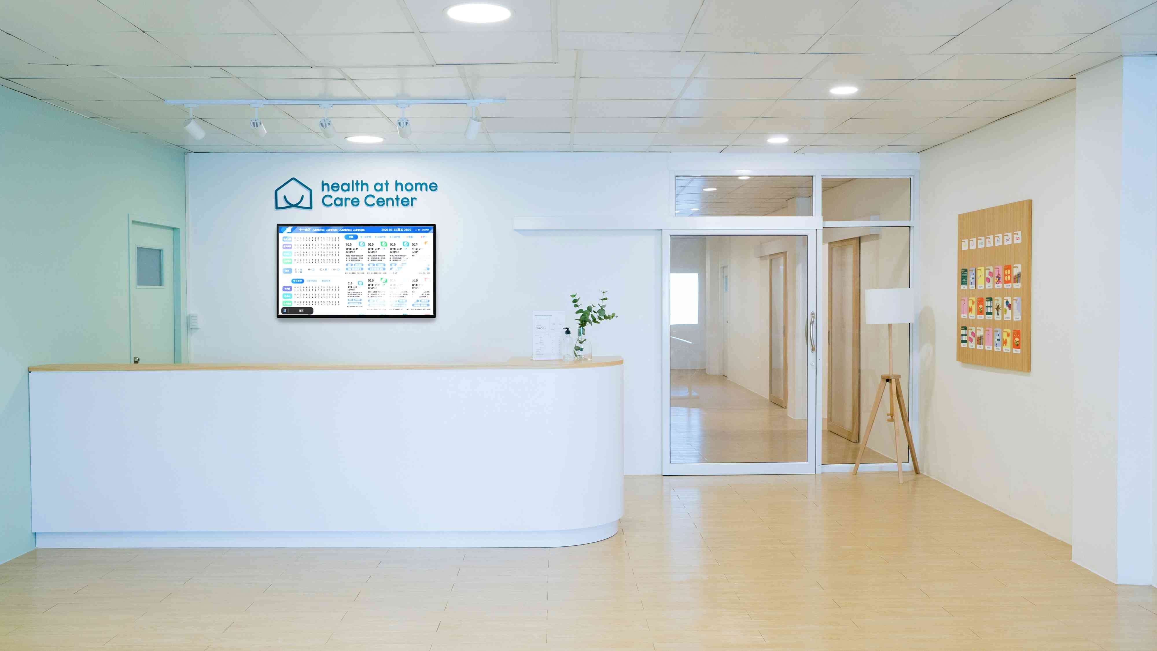 Wall-mounted digital signage screen displaying patient queue and schedule information in a modern healthcare center reception area
